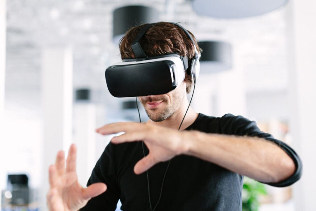 Mann steht in einem Büro, nutzt eine Virtual Reality Brille und gestikuliert.